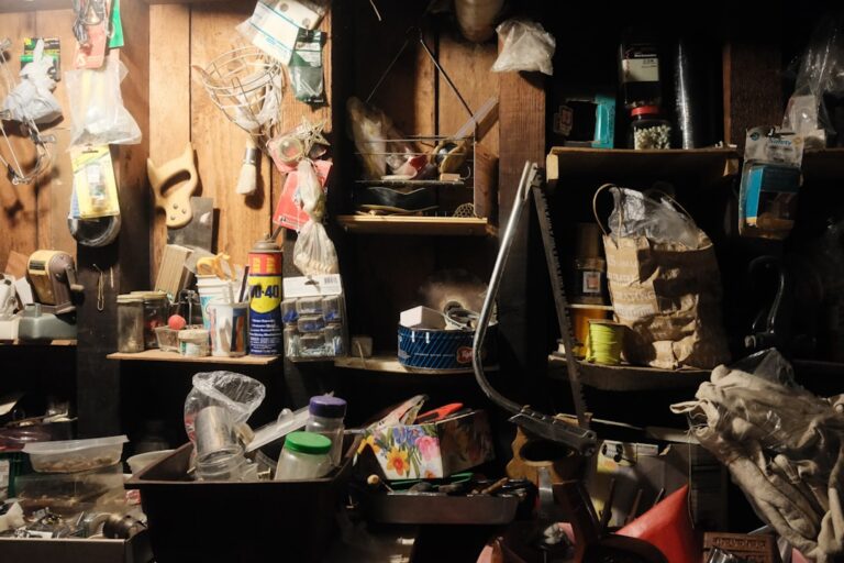 A person inspecting a hydraulic cylinder and hoses in a well-organized garage storage area.